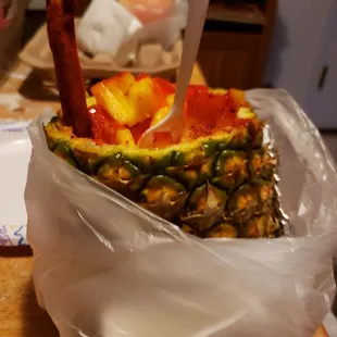 Pineapple with chili powder and chamoy, rainbow snow cone behind.