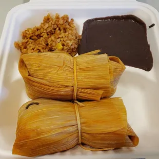 a white styrofoam container filled with rice, beans, and a side of black beans