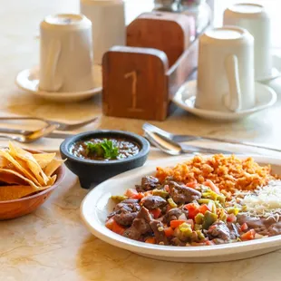 a plate of mexican food and a bowl of chips