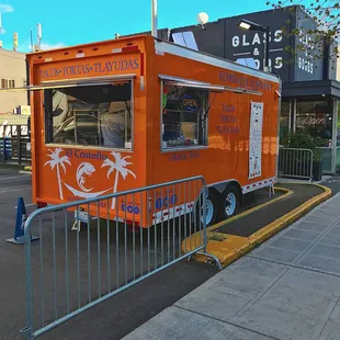 an orange food truck parked on the side of the road