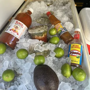 limes, limes, and hot sauces in a cooler
