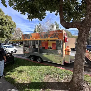 a food truck parked next to a tree