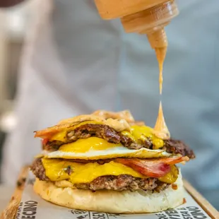 a burger being drizzled with mustard