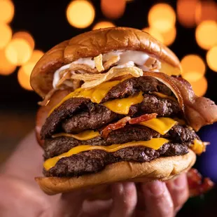 a hand holding a large cheeseburger