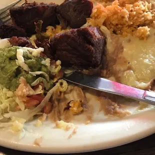 Carnitas with rice, refried beans with cheese, guacamole, lettuce and tomatoes.