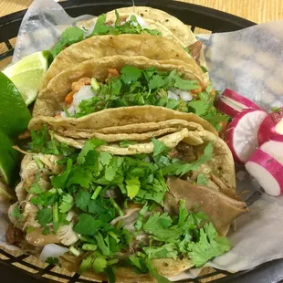 a plate of tacos with a side of radishes