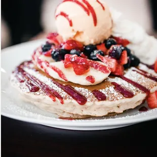 a stack of pancakes topped with berries and ice cream