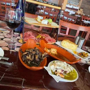 a table with plates of food and a glass of wine