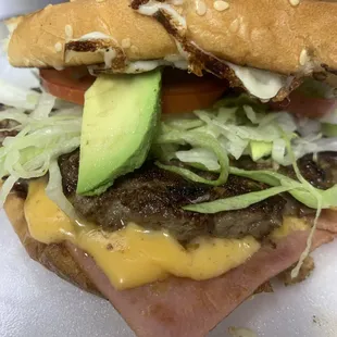 a hamburger with lettuce, tomato, and avocado
