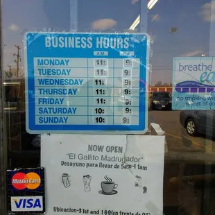 a business hours sign in a window