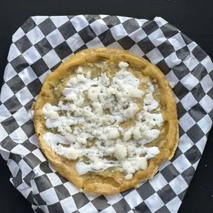 Picadita: soft fried corn dough layered with mild sauce, sour cream and queso fresco.