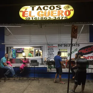 a group of people sitting at tables in front of a restaurant