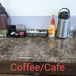 a coffee / cafe counter with a coffee pot, a cup of coffee, and other items