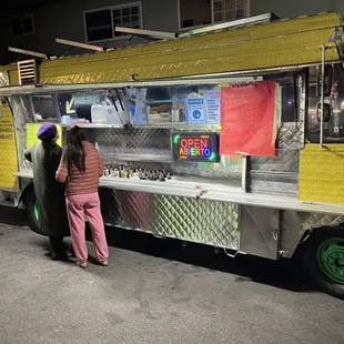 a woman standing in front of a food truck