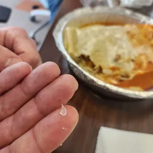 a person holding a piece of lasagna