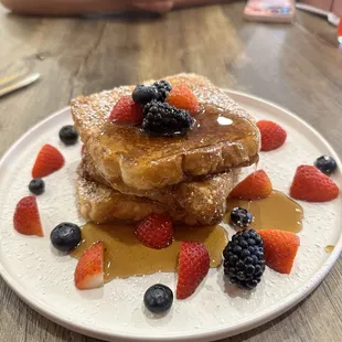 a stack of french toast with berries and syrup