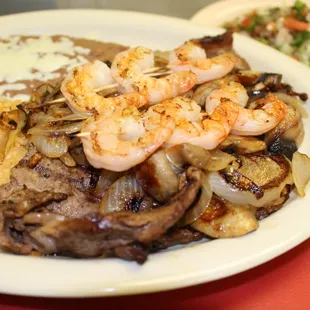Delicious steak with shrimp, grill onion, mushrooms, salad rice and beans.