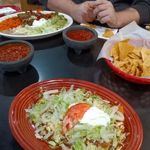 Burrito and enchilada combo on the bottom fajitas on the top chips regular salsa hot salsa.