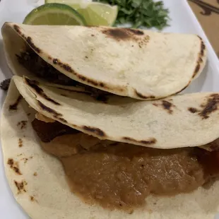 Refrito and bacon taco, fat barbacoa taco in flour tortillas
