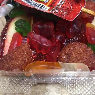 Mexican candy assortment box with a sliced candied apple, Chamoy candies, gummy bears and worms, lollipops and more.