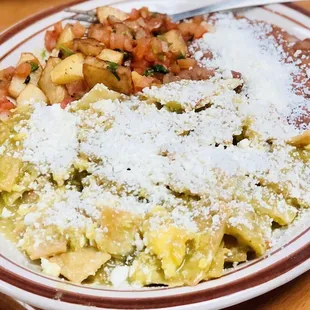 Green chilaquiles (scrambled egg mixed in) with potatoes, refried beans, and pico de gallo