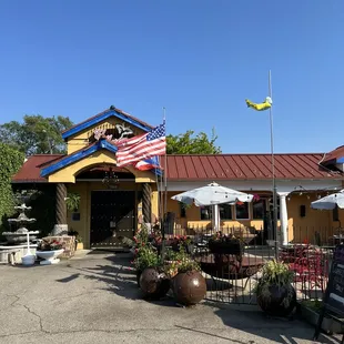 the front of a restaurant with tables and umbrellas