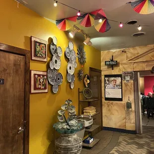 a yellow wall with colorful umbrellas hanging from the ceiling