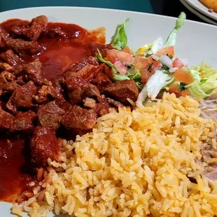 Chile colorado with tasty rice and refried beans.