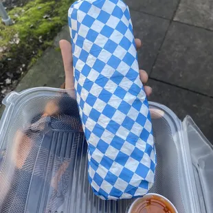a sandwich wrapped in a blue and white checkered paper