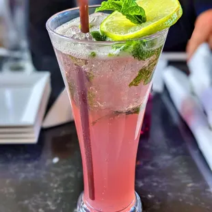 a pink cocktail with lime and mint