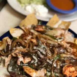 Fajita nachos El Molcajete : Shrimp, Grilled Steak, Grilled chicken with grilled onions, bell peppers and tomato