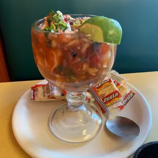 Calamari and seafood cocktail with a slice if lime and crackers.