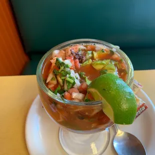 Calamari and seafood cocktail with a slice if lime and crackers.