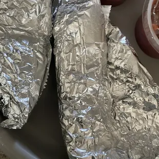 two burritos wrapped in aluminum foil