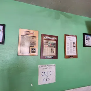 a green wall with pictures and plaques on it