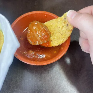 a person dipping a tortilla into a bowl