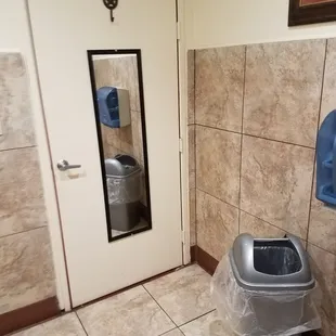 a bathroom with a trash can and mirror