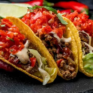 three tacos on a black plate