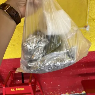 a person holding a plastic bag full of food