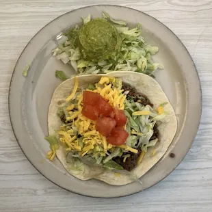 Beef taco with flour tortilla and guacamole salad.