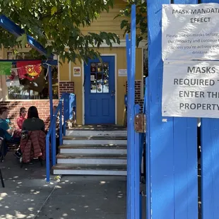 a blue gate with a sign stating masks required to enter the property