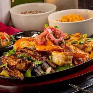 Trio Fajitas Chicken, Steak, And Shrimp Served with rice and beans (black or refried) and handmade tortillas.
