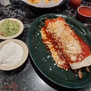 Delicious super steak burrito with side of guacamole and sour cream
