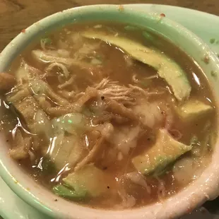 Bowl of chicken tortilla soup with a side of avocado