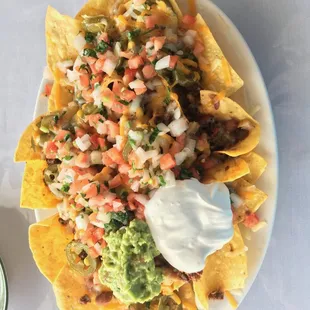 Nachos Fiesta - Tortilla chips served with beef, beans, pico de gallo, lettuce, cheese, cream and guacamole