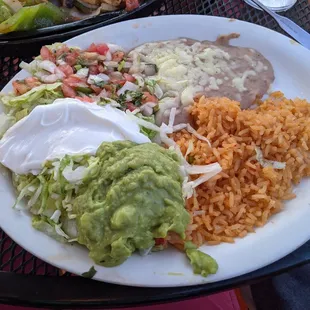 Rice, beans, guac, vegetables, sour cream for chicken fajitas