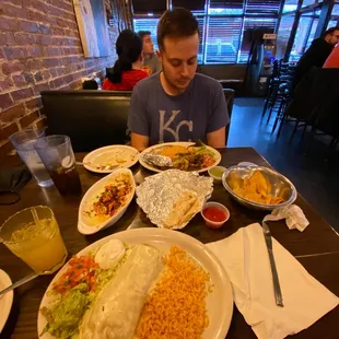 a man sitting at a table with plates of food