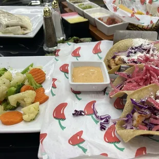 Street taco's with shrimp steams veggies on the side.