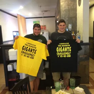 two men holding t - shirts