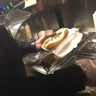 a person serving a hot dog